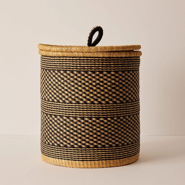 Handwoven lidded basket in natural and black weave with a leather loop handle
