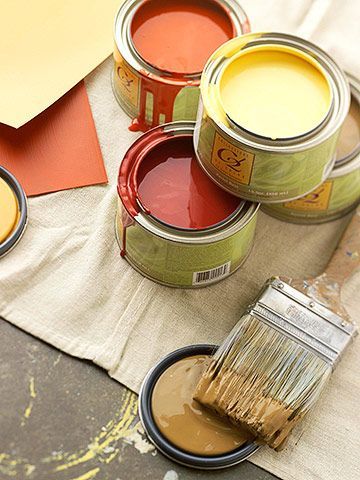 Open tins of warm terracotta and ochre Mix Lab paints with a brush